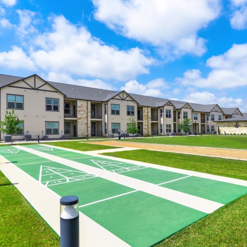 The outdoor recreation area at Retreat at Krum senior living apartments in Krum, TX, featuring a view of the apartments.