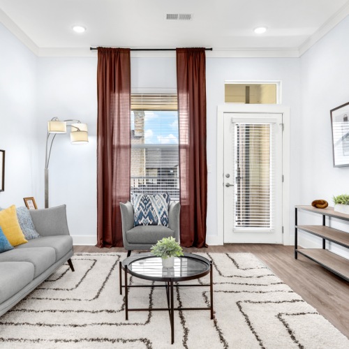 Model living room at Retreat at Krum senior living apartments in Krum, TX, featuring wood grain floor paneling.