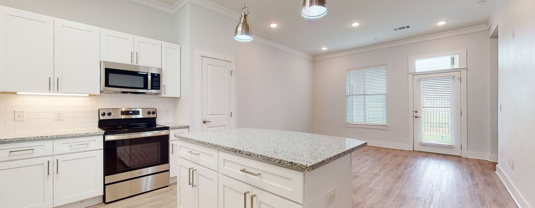 a kitchen with white cabinets & granite island